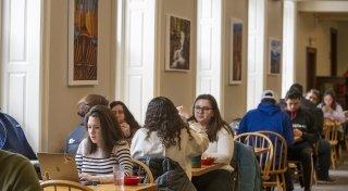 Students sitting down together for a meal and a discussion at several tables throughout Dana Dining Hall.