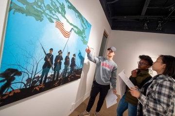 三个学生在画廊里欣赏一件艺术品.